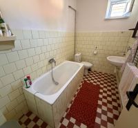 Bathroom with a bathtub, tiled walls, and a sink in a family house.