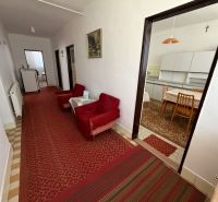 A hallway with carpets and a kitchen in a family house, furnished with stylish chairs and a table.