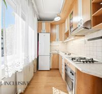 A kitchen in a 3-room apartment with a wooden decor floor and a kitchen unit.