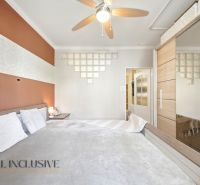 Bedroom with a built-in wardrobe and geometric decor in a 3-room apartment with a wood-patterned floor.