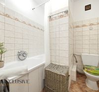A bathroom in a 3-room apartment with a bathtub, a laundry basket, and decorative ceramics.