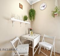 Kitchen corner in a 3-room apartment with a white table, hanging plants, and a wooden decor floor.