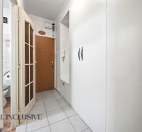 A hallway with white built-in furniture in a 3-room apartment, entrance doors, and tiles.
