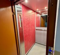 An elevator with red walls in a building; space for a 4-room apartment.