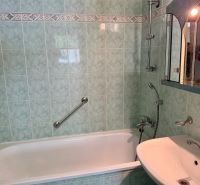 A bathroom with green tiles and a bathtub in a 4-room apartment.
