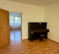 4-room apartment with a piano, wooden decor flooring, white wall, open doors.