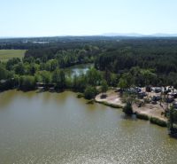 A view of cottages by the water in the Do Gazárky area, Šaštín-Stráže, surrounded by forest.