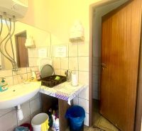 Bathroom with a sink, mirror, soap dispensers, and storage space.