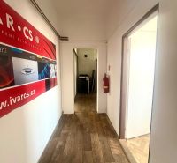 A corridor in commercial premises with a wooden decor floor and a wall poster.