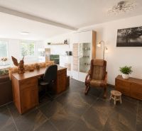 A living room in a cottage with a comfortable armchair and a wooden table.