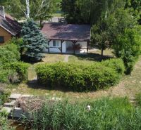 A cottage in Kopčany surrounded by greenery and trees, situated by the water.