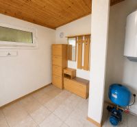 Interior of a cottage with storage furniture, a boiler, and tiled flooring.