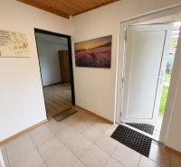 A cottage with tiles, open white doors, and a framed picture of flowers.
