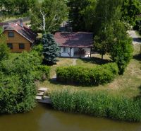 Green garden, a cottage by the water in Kopčany surrounded by greenery and trees.