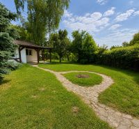 A cottage in Kopčany surrounded by greenery with a landscaped garden and an access path.