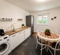 A kitchen in a cottage with white furniture and a decorated table.