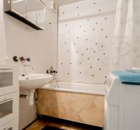 A bathroom with a bathtub, sink, and washing machine in a 3-room apartment.