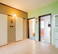 A hallway in a 3-room apartment with a ceramic floor, green wall, and bright lighting.
