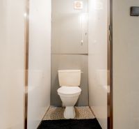 A bathroom in a 3-room apartment with white walls and a toilet.