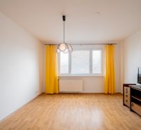 Living room in a 3-room apartment with a wooden decor floor and yellow curtains.