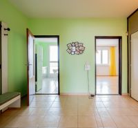 Interior of a 3-room apartment with tiles and light green walls, doors to the kitchen and living room.