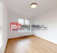 A room in a three-room apartment with a wooden decor floor and a large window.