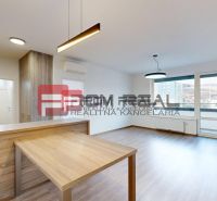 Living space in a 3-room apartment with a wooden decor floor and a kitchenette.