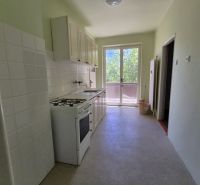 A kitchen in a 3-room apartment with a stove and a view of the balcony.