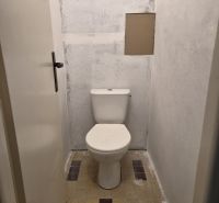 A simple toilet in a 3-room apartment with unobtrusive tiles.