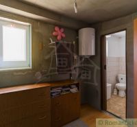 A cabin with a wooden decor floor, a dresser, a boiler, and an entrance to the bathroom.