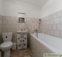 A bathroom in a cottage with a bathtub, sink, and toilet, with tiles on the walls.