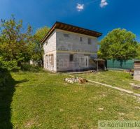 A cottage in Bernolákovo surrounded by green trees, with a spacious lawn and blue sky.