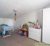 Interior of a cabin with a sloped ceiling, a bed on a ball, and decorations on the dresser.