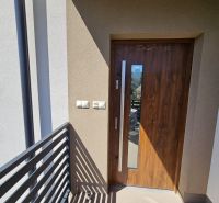 Entrance door to a one-room apartment with a wood decor and a balcony railing.