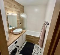 Bathroom in a 3-room apartment with a washing machine and a wooden decor floor.