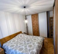 Bedroom with wood-patterned flooring and a large bed in a 3-room apartment.