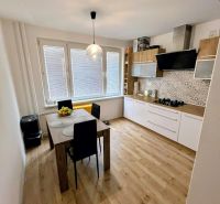 A kitchen in a 3-room apartment with a wooden decor floor and a dining table.