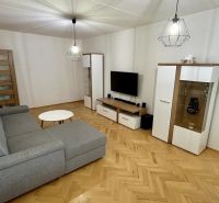 Living room with a sofa, television, and wood-patterned flooring in a 3-room apartment.