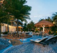 An evening view of a tropical resort with a pool in Paje surrounded by palm trees.