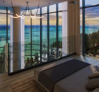 A bedroom in a studio apartment with large windows and an ocean view.