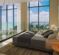 A glazed bedroom in a studio apartment with an ocean view and wood-patterned flooring.
