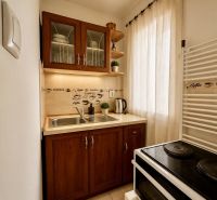 A kitchenette in a studio apartment with two cabinets, a curtain, and an electric stove.