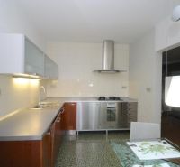 A kitchen in a 3-room apartment with metal appliances and stylish lighting.