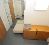 Entrance hallway of a 3-room apartment with a coat rack, bench, and cabinet on tiles.