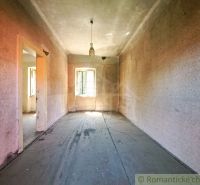 An older room in a family house with worn-out wallpaper and a simple light fixture.