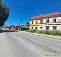A street with a historic family house in Klátova Nová Ves under a blue sky.