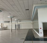 Commercial spaces with white tiles, columns, and stairs in the background.
