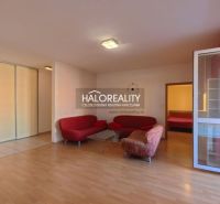 Living room with wood-patterned flooring and a red sofa in a three-room apartment.