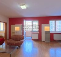 Living room in a three-room apartment with a wooden decor floor and a red wall.