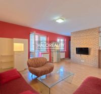 Living room with a sofa, brick wall, and wood-patterned flooring in a three-room apartment.